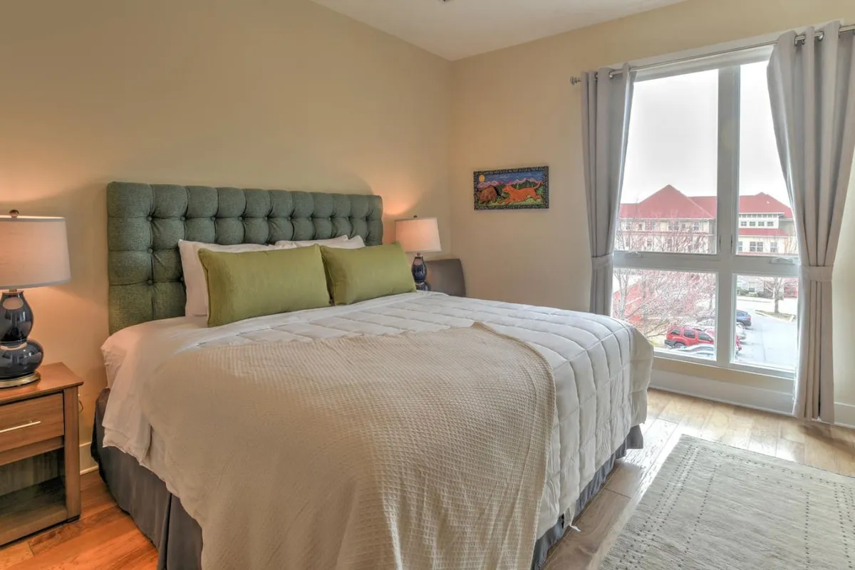 A cozy bedroom with a bed, window, and inviting artwork. Sunlight streams in, offering a glimpse of peaceful mornings and restful nights inside the condo. The room feels both relaxing and welcoming, with soft lighting and a sense of privacy.